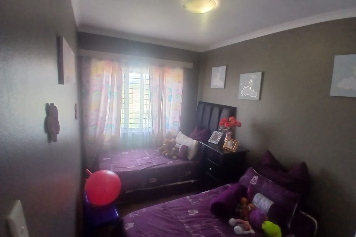 A compact bedroom featuring dark painted walls, a window with security bars, and a ceiling light fixture.