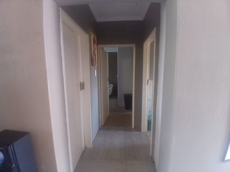 A functional hallway featuring tiled flooring and access to multiple rooms within the apartment.