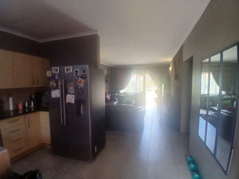Open-plan living area featuring tiled floors, built-in kitchen cabinetry, and a sliding glass door leading to an outdoor space.