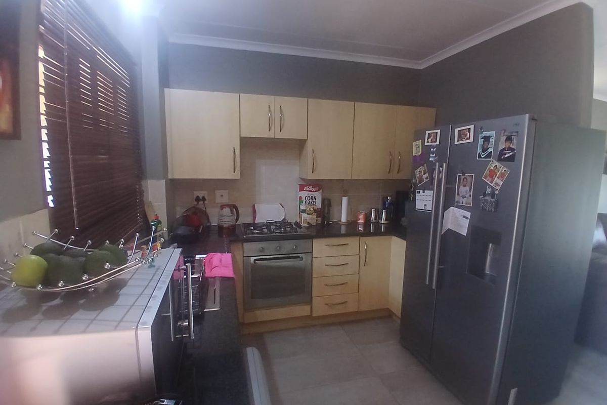 A functional kitchen featuring light wood cabinetry, dark granite countertops, a gas hob, and an integrated oven, finished with neutral floor tiles.
