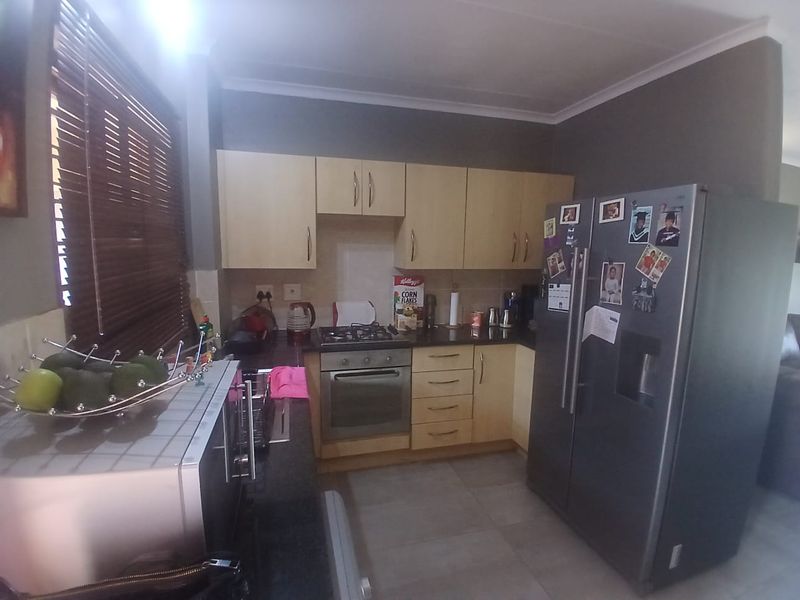 A functional kitchen featuring light wood cabinetry, dark granite countertops, a gas hob, and an integrated oven, finished with neutral floor tiles.