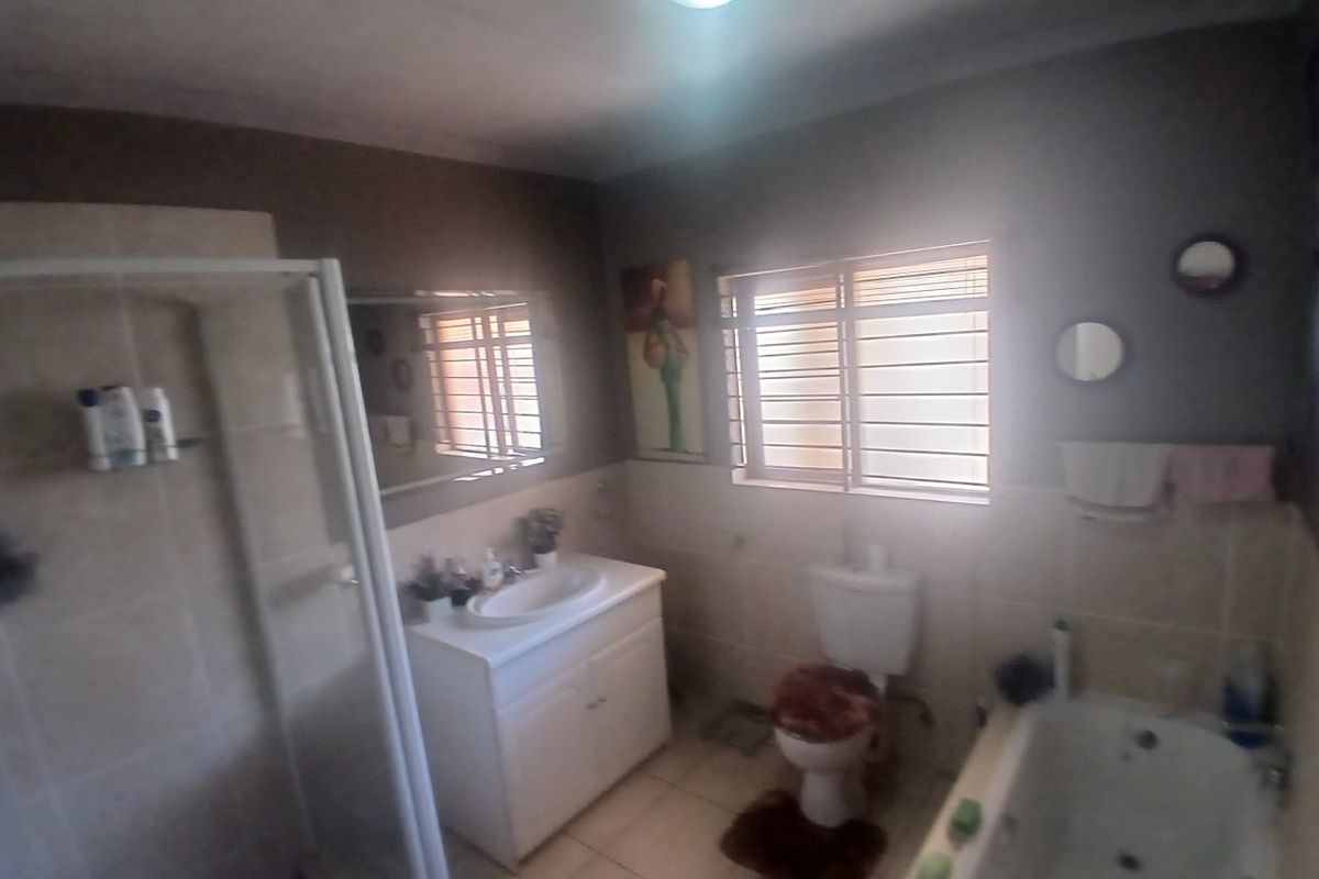 A functional bathroom featuring a separate shower enclosure, bathtub, vanity basin, and toilet, finished with tiled walls and floors.