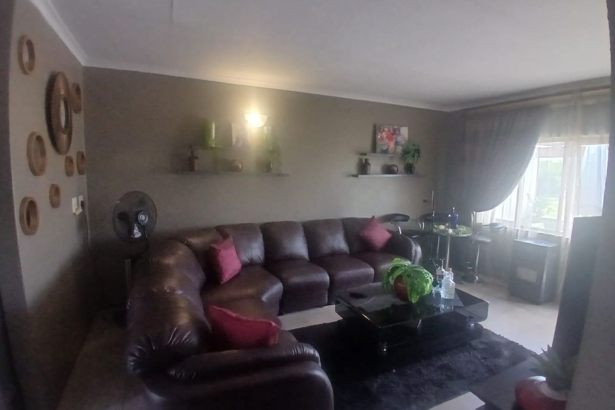 A comfortable living room featuring tiled flooring, neutral wall tones, and large windows that provide natural light.