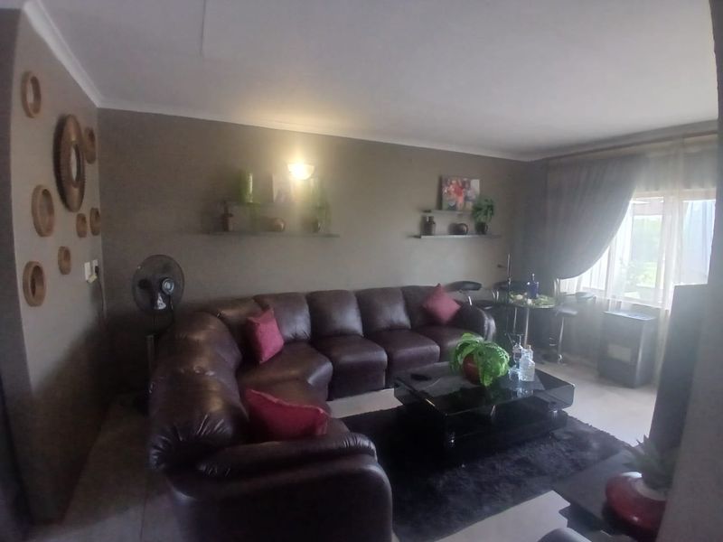 A comfortable living room featuring tiled flooring, neutral wall tones, and large windows that provide natural light.