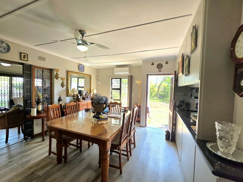 Open-plan dining and kitchen area featuring laminate flooring, ceiling fan, split-system air conditioning, and direct access to the outdoor space.