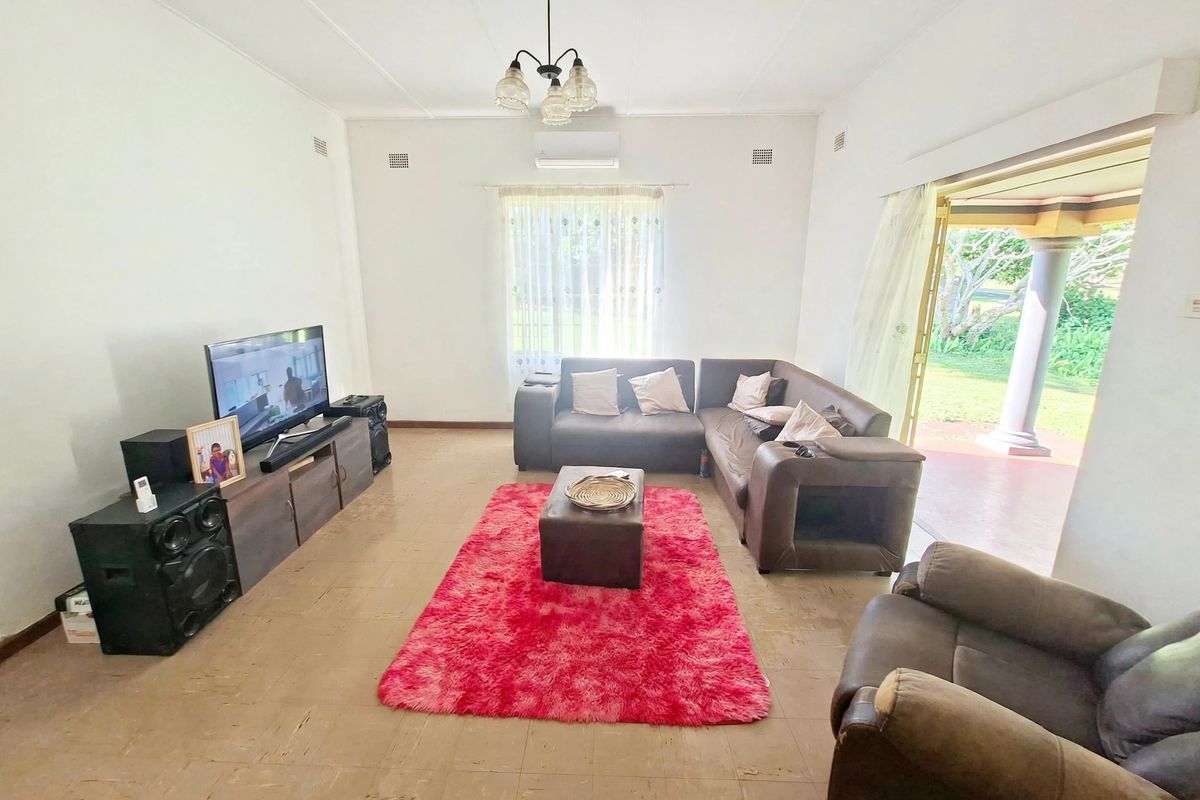 A spacious living room featuring tiled flooring, a split-system air conditioner, and direct access to an outdoor patio area through sliding glass doors.