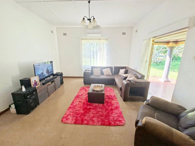 A spacious living room featuring tiled flooring, a split-system air conditioner, and direct access to an outdoor patio area through sliding glass doors.