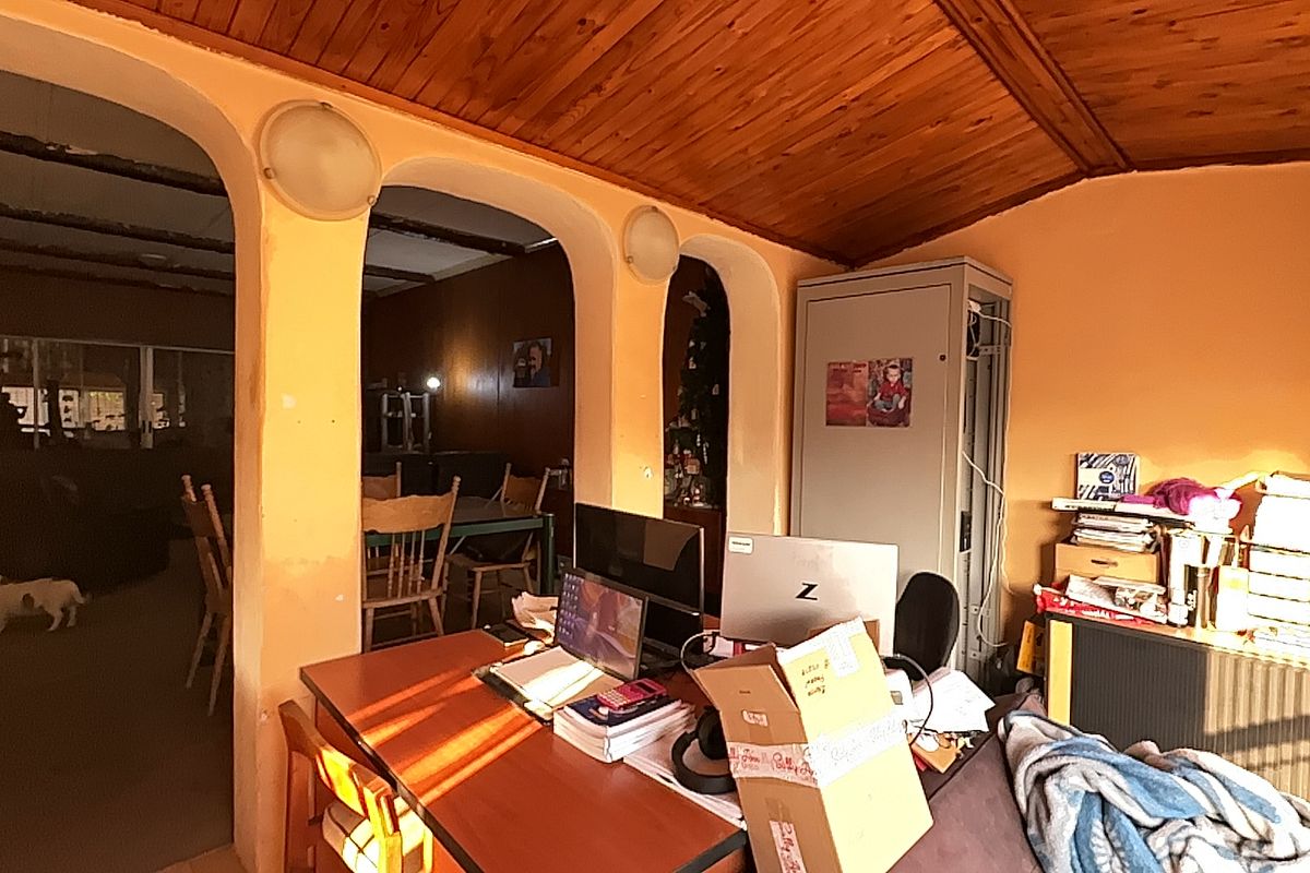 A living area featuring a timber ceiling and distinctive arched wall openings, providing a view into the adjacent dining space.