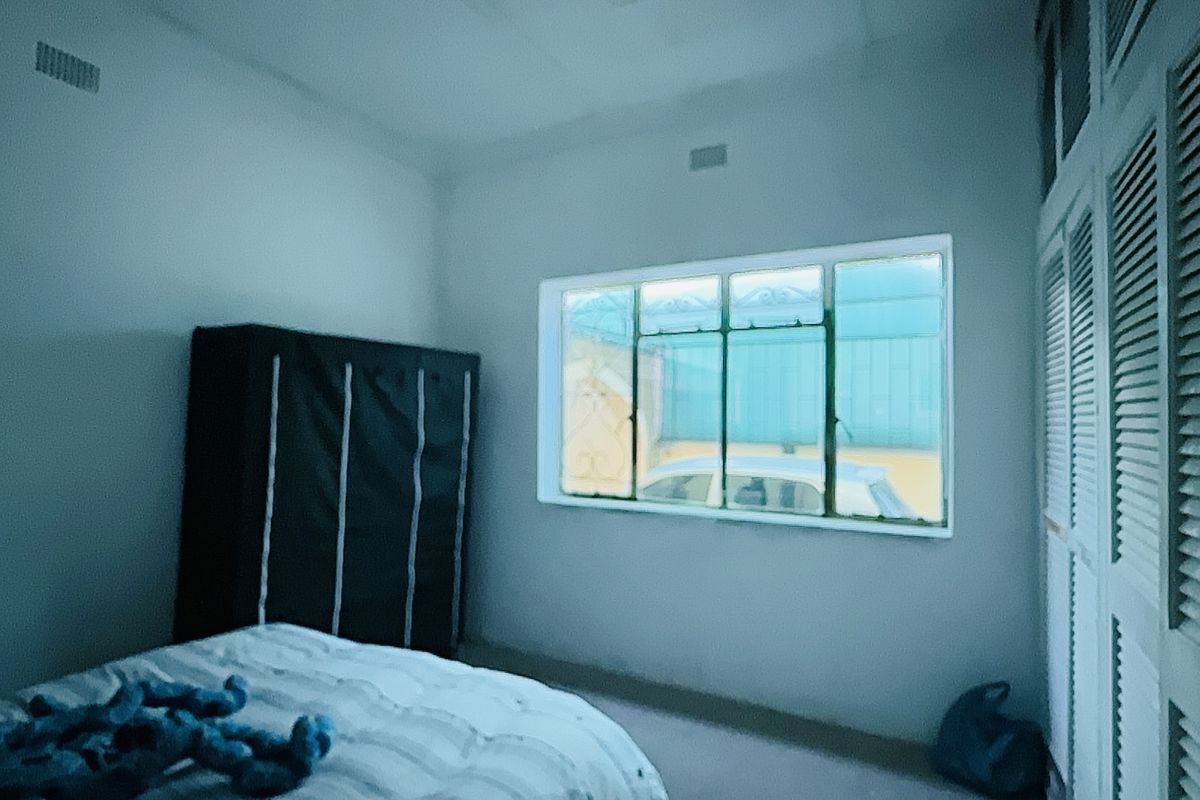 A bedroom featuring built-in cupboards with louvered doors and a large window providing natural light.