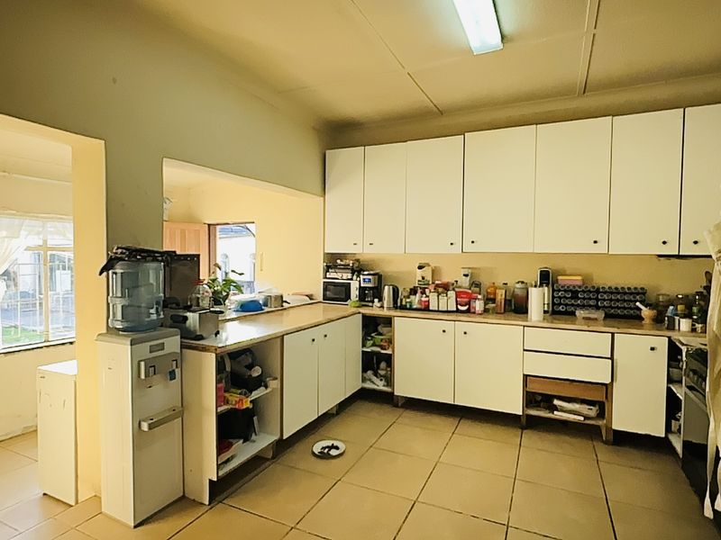 A functional kitchen featuring built-in cabinetry, tiled flooring, and ample counter space, offering significant potential for modernization and aesthetic upgrades.