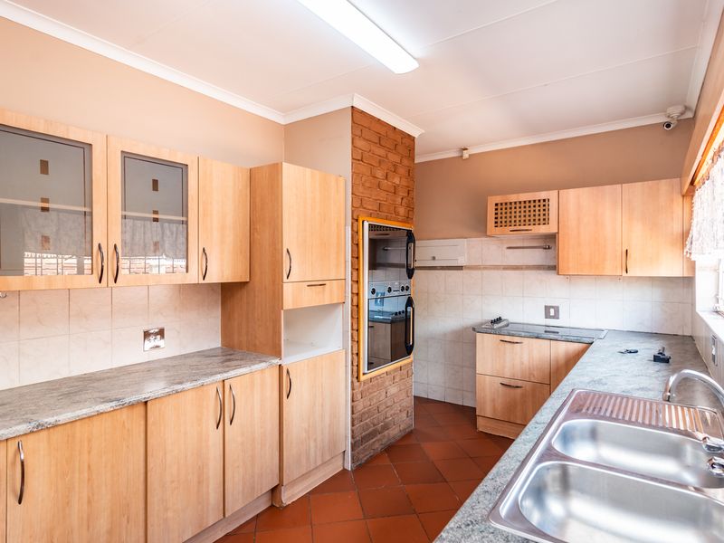Functional kitchen featuring light wood cabinetry, granite-look laminate countertops, a built-in double oven, and a classic terracotta tiled floor.