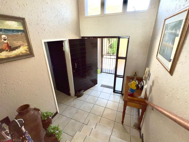 Entrance foyer featuring tiled flooring, textured walls, and a secure front door with clerestory windows providing natural light.