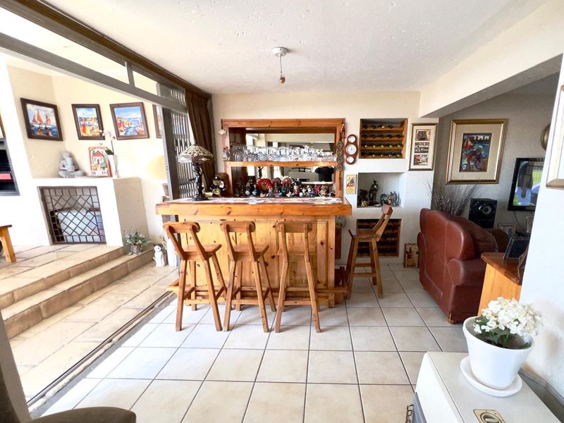 A spacious indoor bar area featuring a built-in wooden counter, integrated wine storage, and direct access to an outdoor patio through sliding glass doors.