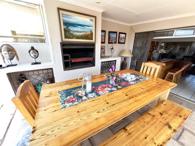 Covered patio area featuring a built-in braai, tiled flooring, and direct access to the interior living space through a sliding security gate.