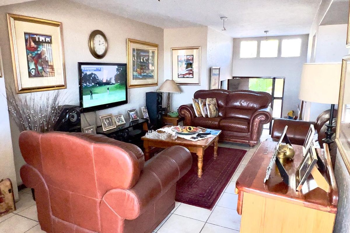 A comfortable living room featuring tiled flooring, recessed lighting, and clerestory windows that provide natural light to the space.