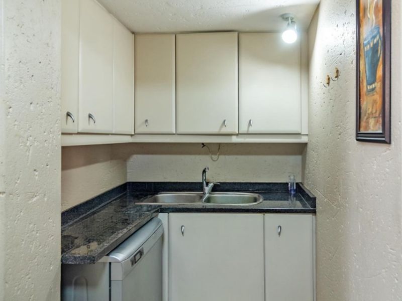 A compact scullery area featuring built-in cabinetry, a double basin sink, and granite countertops, providing functional prep and wash-up space.