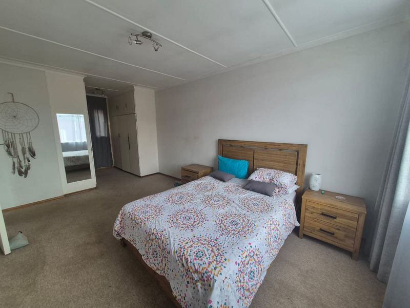 A spacious bedroom featuring built-in cupboards, neutral wall finishes, and carpeted flooring, offering a functional layout with ample storage space.