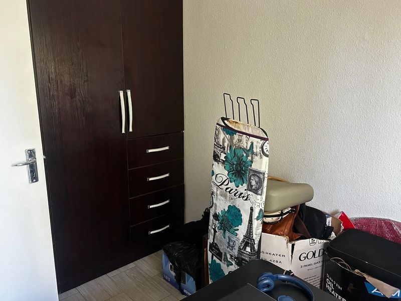 A bedroom featuring a dark wood built-in wardrobe with integrated drawers and modern handles.