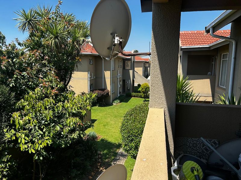 A view from a balcony overlooking the apartment complex garden and surrounding residential units.