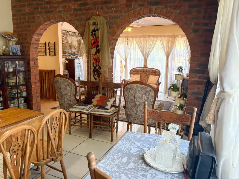 Open plan living and dining area featuring distinctive exposed brick arches and tiled flooring, creating a connected and traditional living space.