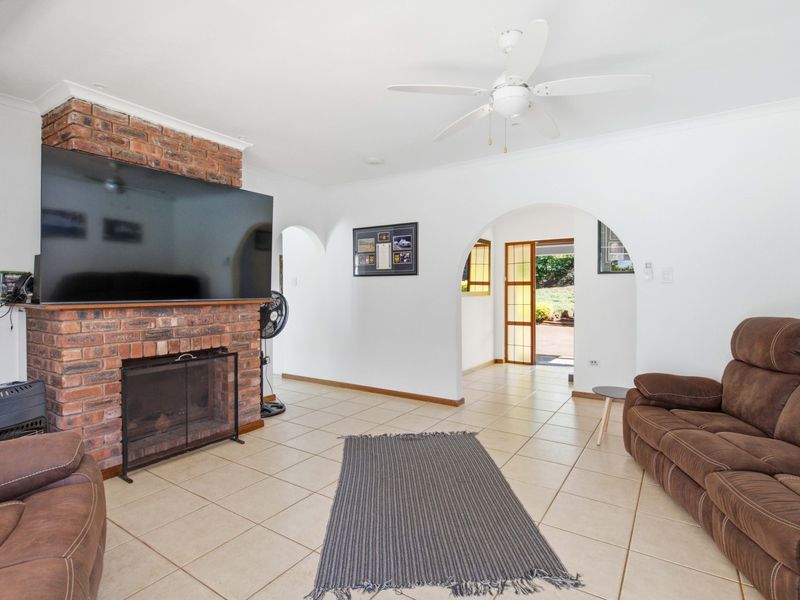Spacious living room featuring an exposed brick fireplace, tiled flooring, and arched architectural details leading to an outdoor area.
