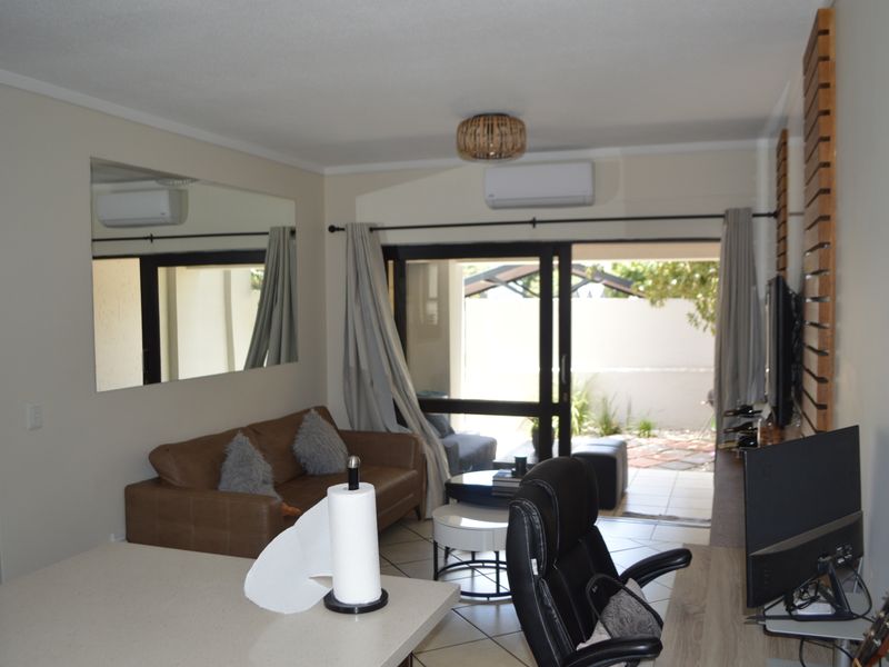 An open-plan living area featuring tiled floors, air conditioning, and a sliding glass door providing direct access to an outdoor patio space.