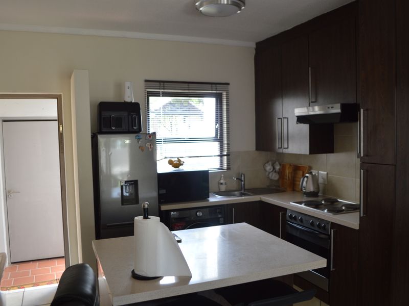 Functional kitchen featuring dark wood cabinetry, stone countertops, a central island, and integrated appliances including an oven and hob.