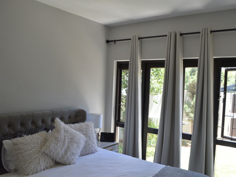 A well-lit bedroom featuring large windows with security bars and neutral wall finishes, providing a bright and comfortable living space.