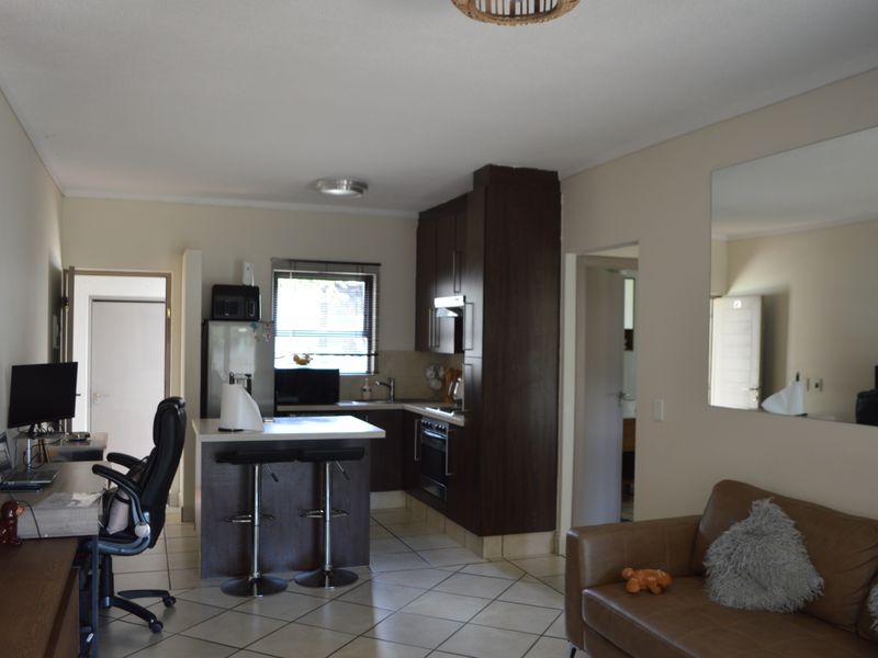Open-plan living area featuring a functional kitchen with dark cabinetry, integrated oven, and a central island, seamlessly connected to the lounge space.
