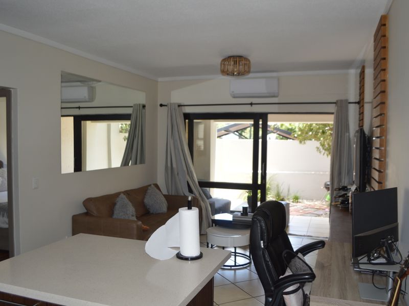Open-plan living area featuring tiled floors, a split-system air conditioner, and sliding glass doors providing direct access to the outdoor patio space.