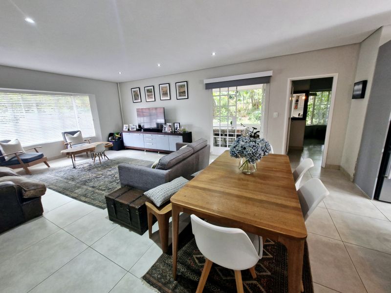 Spacious open-plan living and dining area featuring neutral tiled flooring, recessed lighting, and direct access to an outdoor patio through a classic french door.