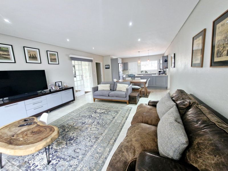 Spacious open-plan living and dining area featuring tiled floors, recessed lighting, and a modern kitchen with ample cabinetry and a functional island.