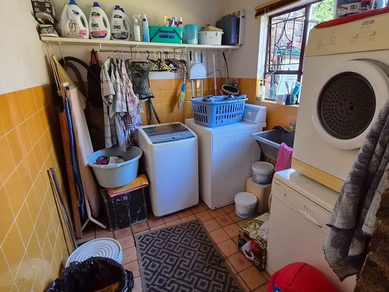 Functional laundry room featuring tiled walls, built-in shelving, and a utility sink, providing a practical space for washing and storage needs.