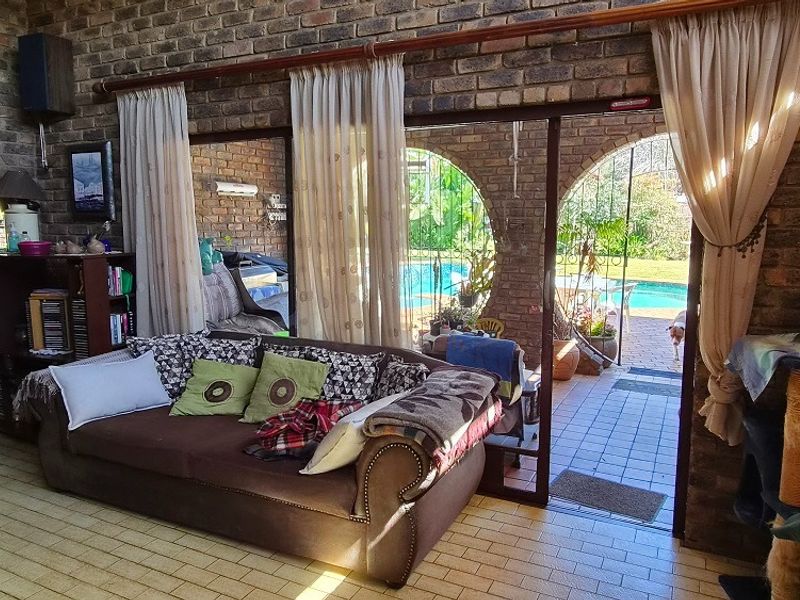 Spacious living area featuring exposed brick walls, tiled flooring, and large sliding glass doors providing direct access to the outdoor pool area.