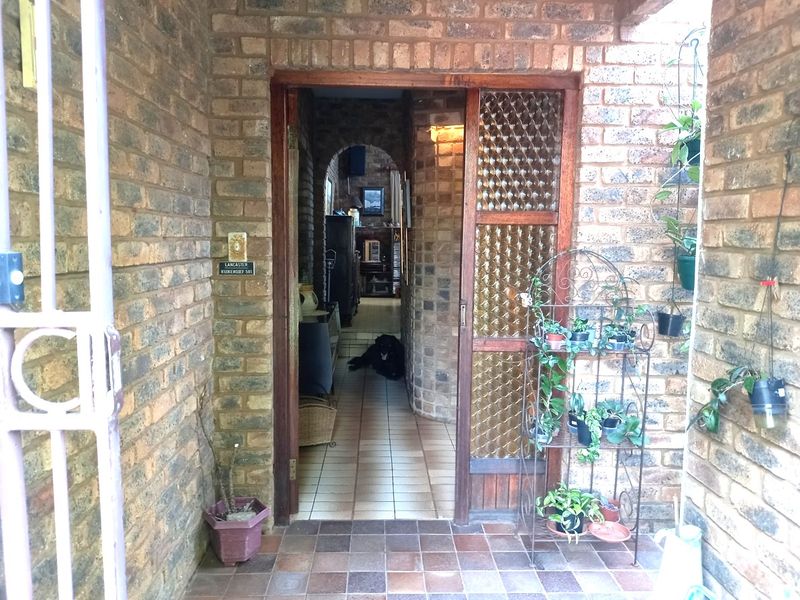 Entrance area featuring exposed brickwork, tiled flooring, and an arched doorway leading into the home interior.