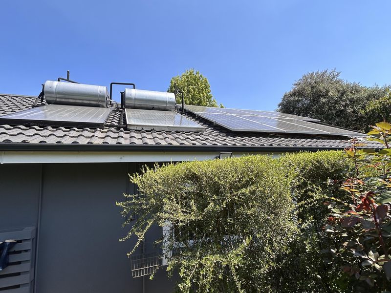 Rear view of the property roof featuring installed solar water heating geysers and photovoltaic solar panels on a tiled roof structure.
