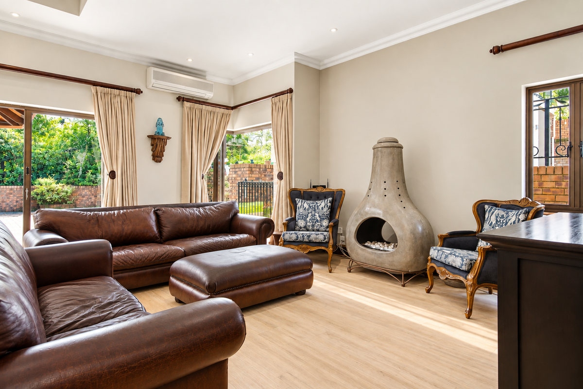 Spacious living room featuring light laminate flooring, recessed downlights, a modern freestanding fireplace, and large sliding glass doors providing access to the garden.
