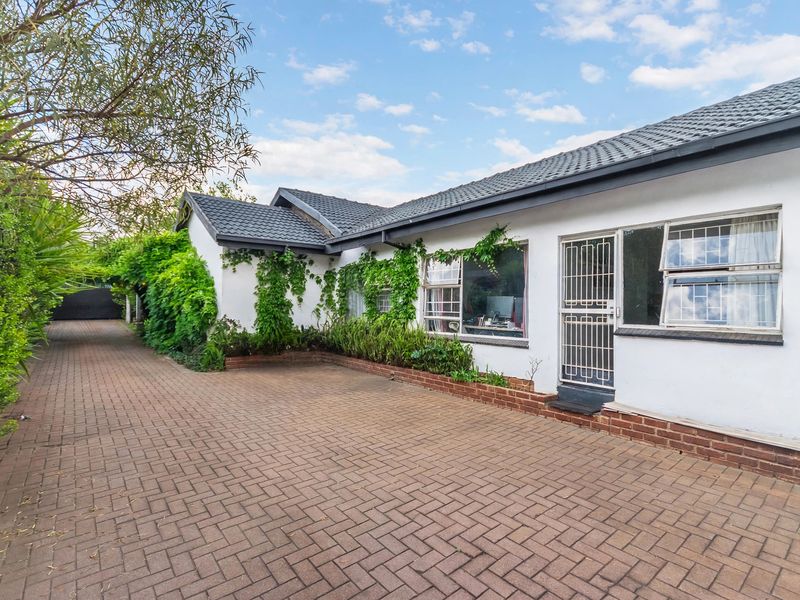 Front exterior view of the property featuring a paved driveway, tiled roof, and secure entrance with established garden greenery.