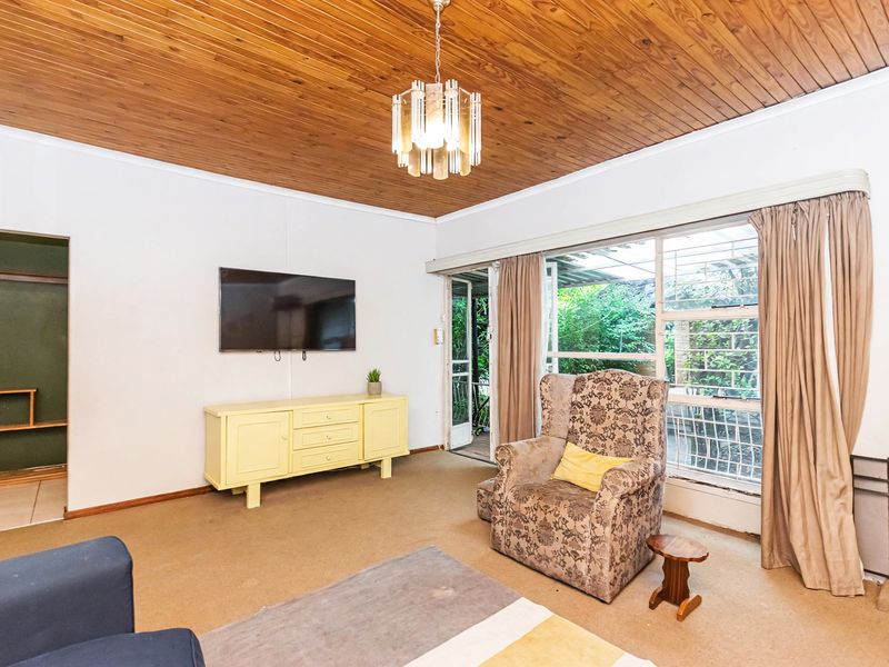 A living room featuring a timber ceiling, fireplace, and sliding glass door access to the garden, with carpet flooring throughout.