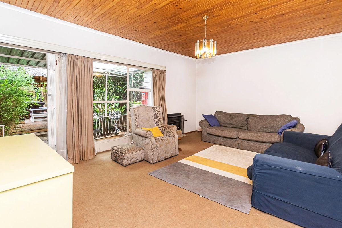 Spacious living room featuring a distinctive timber-clad ceiling, built-in fireplace, and large sliding glass doors providing direct access to the outdoor patio area.