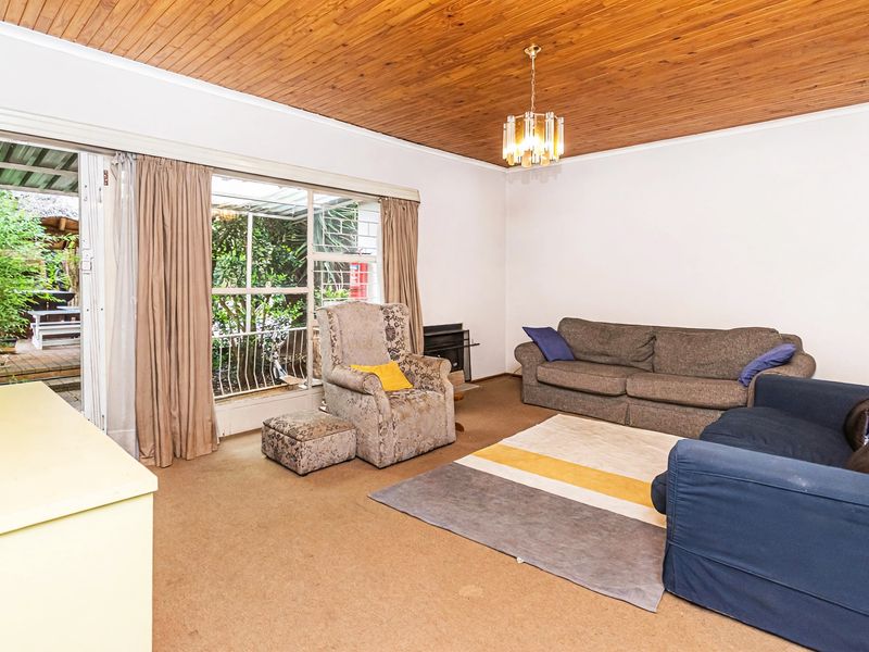 Spacious living room featuring a distinctive timber-clad ceiling, built-in fireplace, and large sliding glass doors providing direct access to the outdoor patio area.