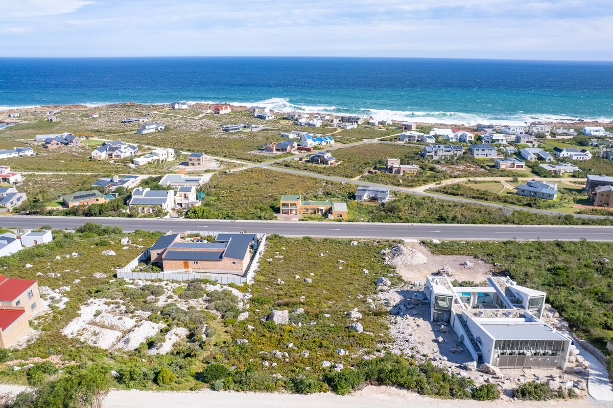An aerial view of a coastal residential area featuring vacant land plots and established homes near the ocean.