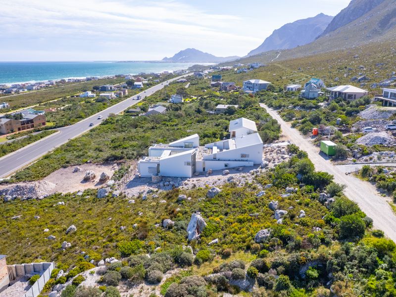 Aerial view of a residential property situated in a coastal landscape with mountain views and convenient road access.