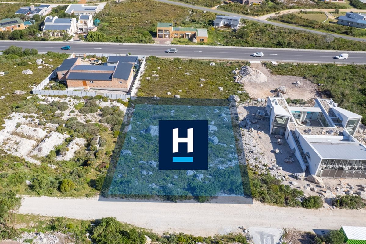 Aerial view of a vacant residential plot featuring natural rocky terrain and indigenous vegetation in a developed coastal estate.