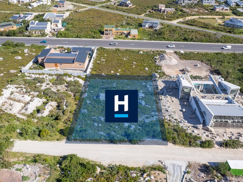 Aerial view of a vacant residential plot featuring natural rocky terrain and indigenous vegetation in a developed coastal estate.
