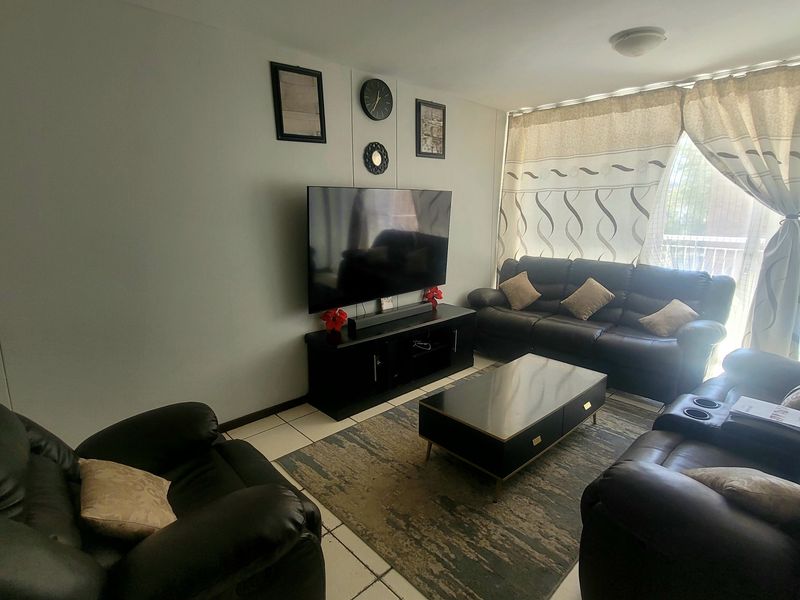 A comfortable living room featuring tiled flooring and a sliding glass door that provides access to an outdoor area.