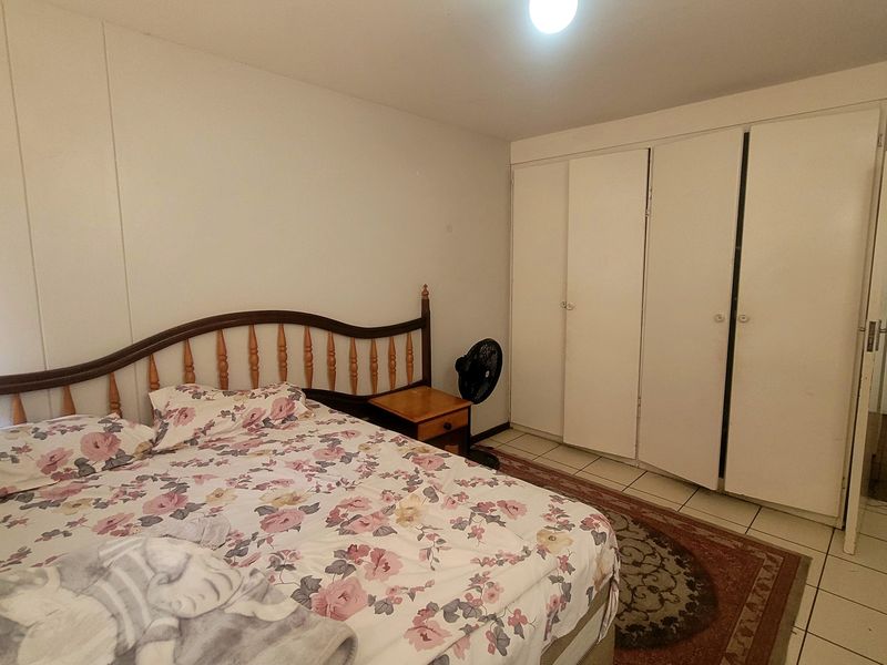 A bedroom featuring tiled flooring and built-in cupboards, offering a functional space with potential for modern updates.