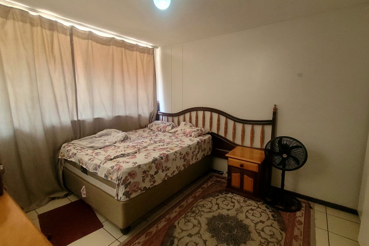 A functional bedroom featuring tiled flooring and a built-in cupboard, offering a neutral space ready for personalization.