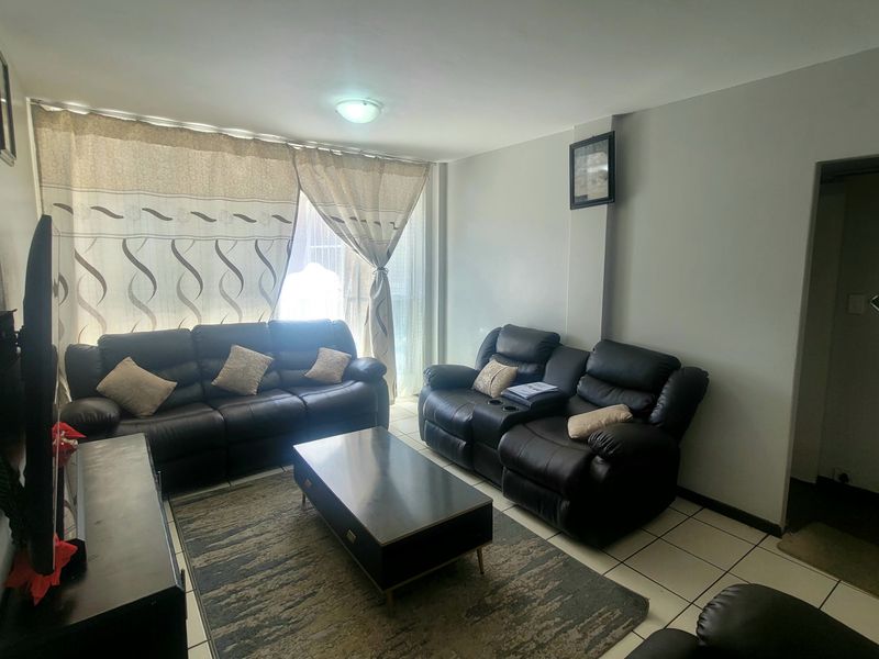 A living room area featuring tiled flooring and a sliding glass door providing natural light.