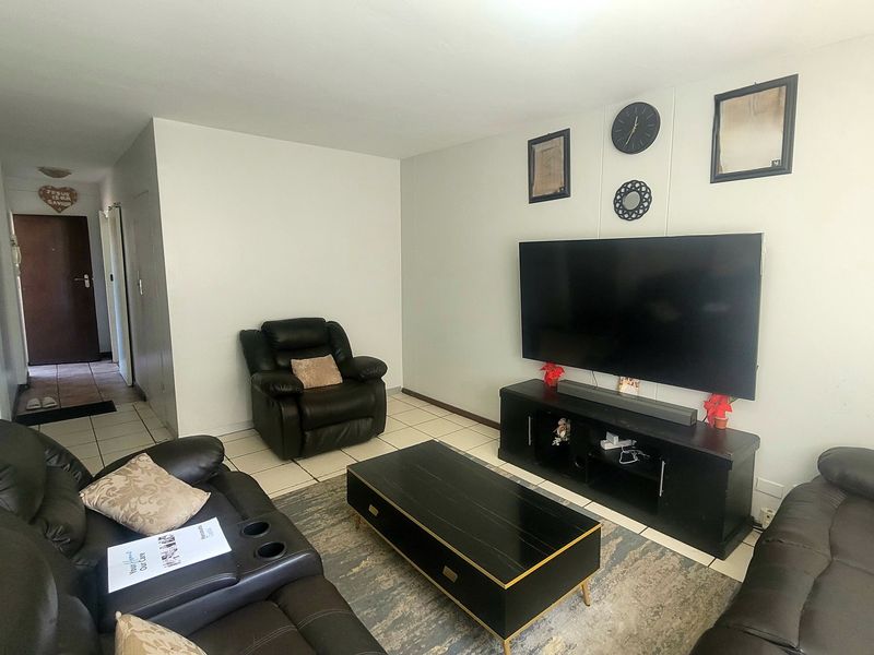 A functional living room featuring tiled flooring and neutral wall finishes, providing a comfortable and well-maintained space for relaxation.